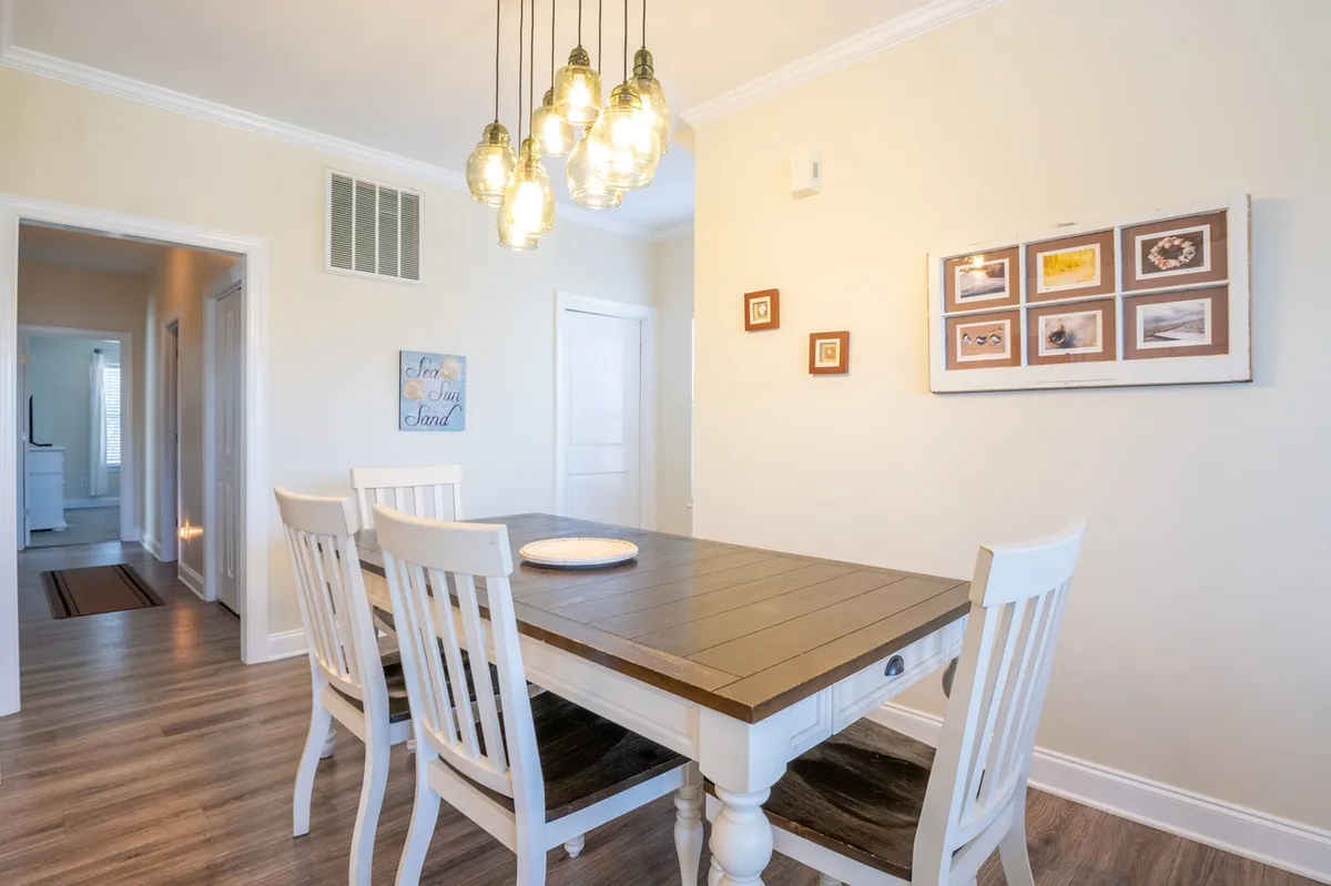 This image displays a charming dining area with a central table, modern light fixtures, and decorative wall frames. The setting is intimate yet inviting, suitable for sharing meals or planning adventures.