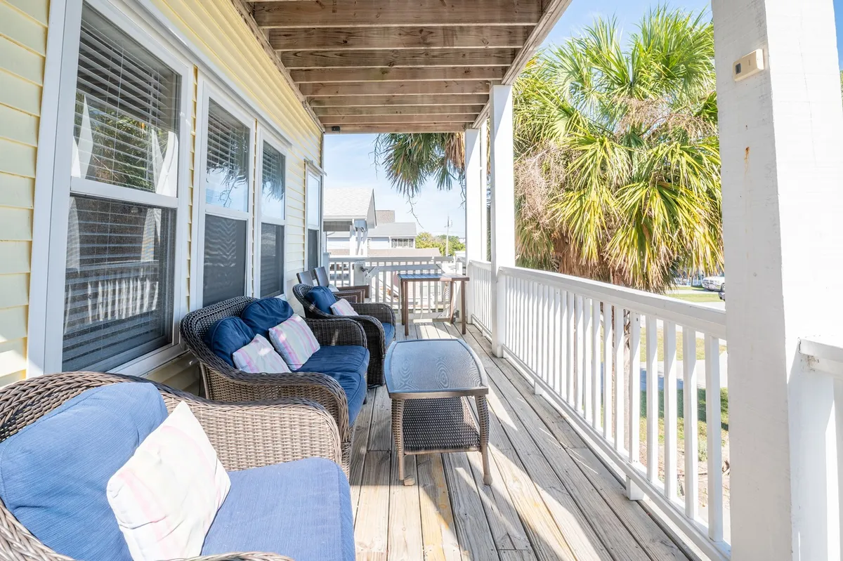 An exterior view focused on comfortable seating with palm trees and a wooden railing, suggesting a serene and inviting outdoor environment ideal for relaxing, reading, or socializing while enjoying sunset views or morning rituals.