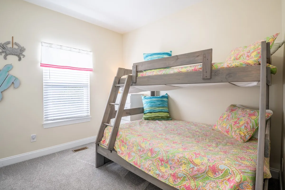 A playful kids' room with a twin-over-full bunk bed, nautical-themed decor, and colorful bedding. The space feels cheerful and ideal for children, friends, or flexible sleeping arrangements, with a sense of fun and imagination.