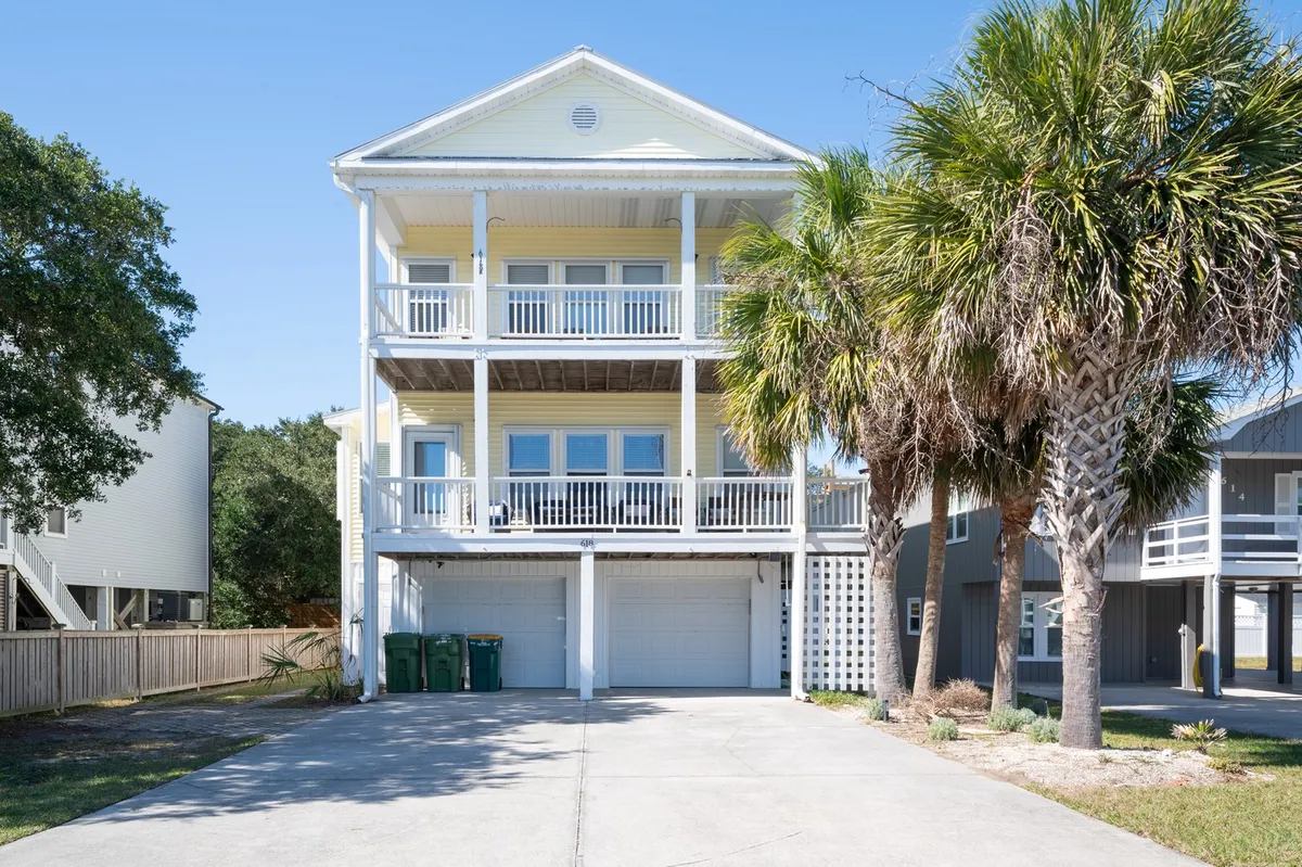 A cheerful exterior shot of a three-story house with large balconies and palm trees, capturing the laid-back, coastal vibe. The home looks inviting, ideal for families to return to after a day at the beach.