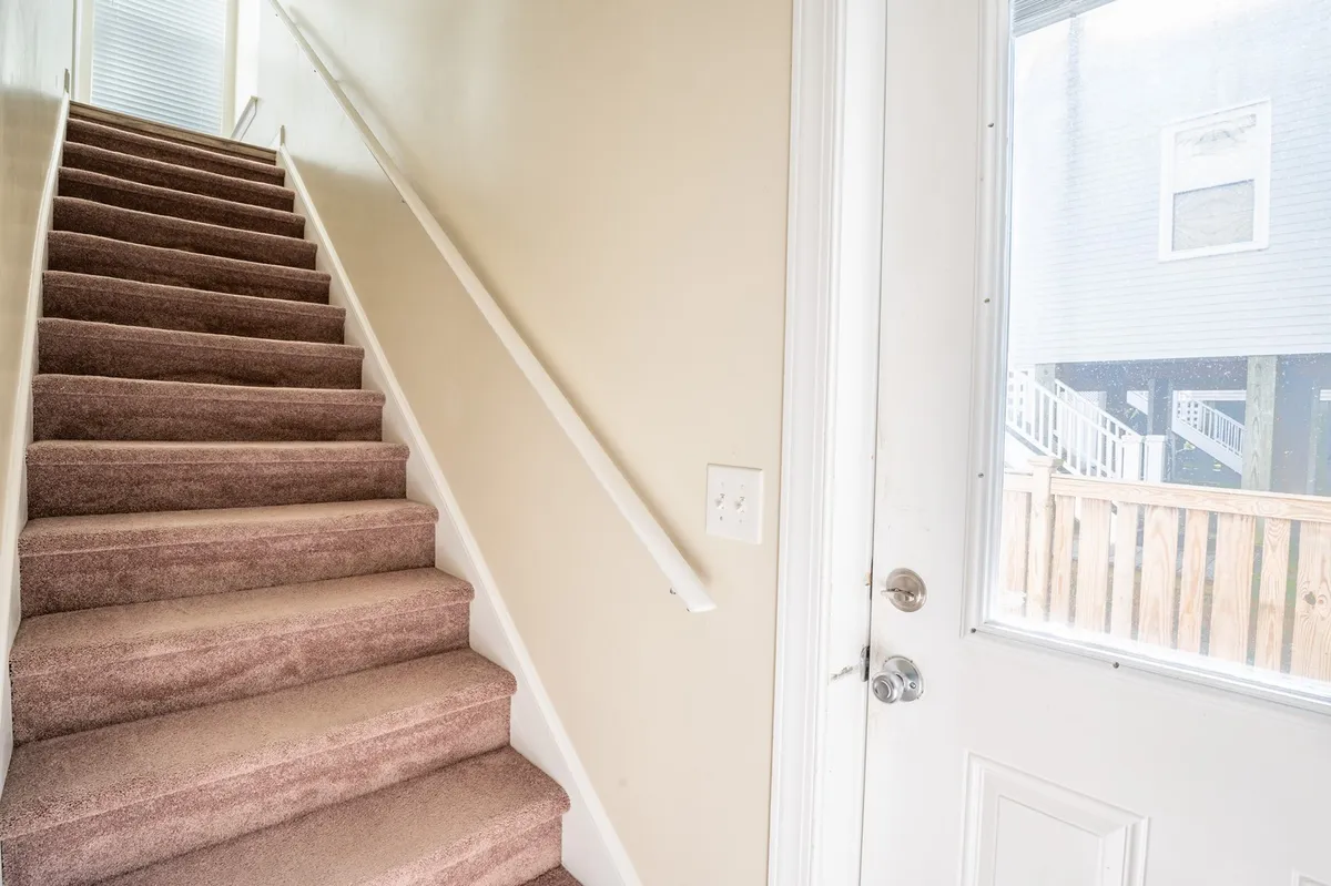An interior view of a staircase and doorway, representing the private inner entryway to the home. The image evokes the sense of a warm welcome and the first moments of arrival, emphasizing comfort and hospitality.