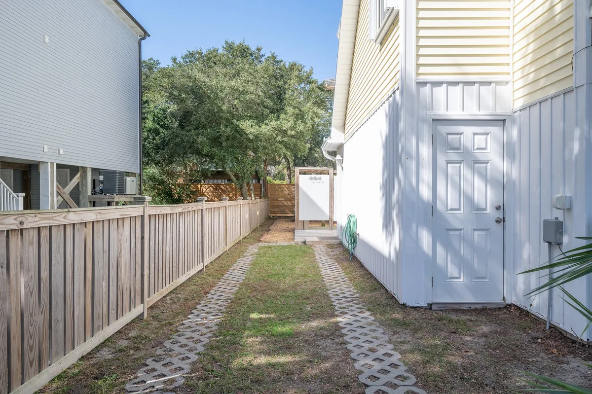 This exterior image features a peaceful pathway leading up to the property’s entrance, framed by a fence and surrounded by mature trees. The outdoor scene suggests a welcoming entry point and hints at relaxing outdoor gatherings or quiet mornings spent with coffee outside.